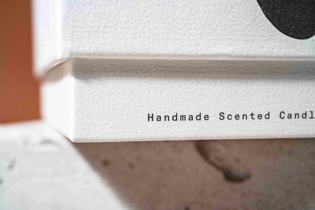 Close up shot of the candle box, showing the text "handmade scented candle"