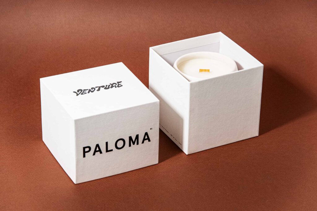 An opened telescopic rigid box with a handmade candle in it.